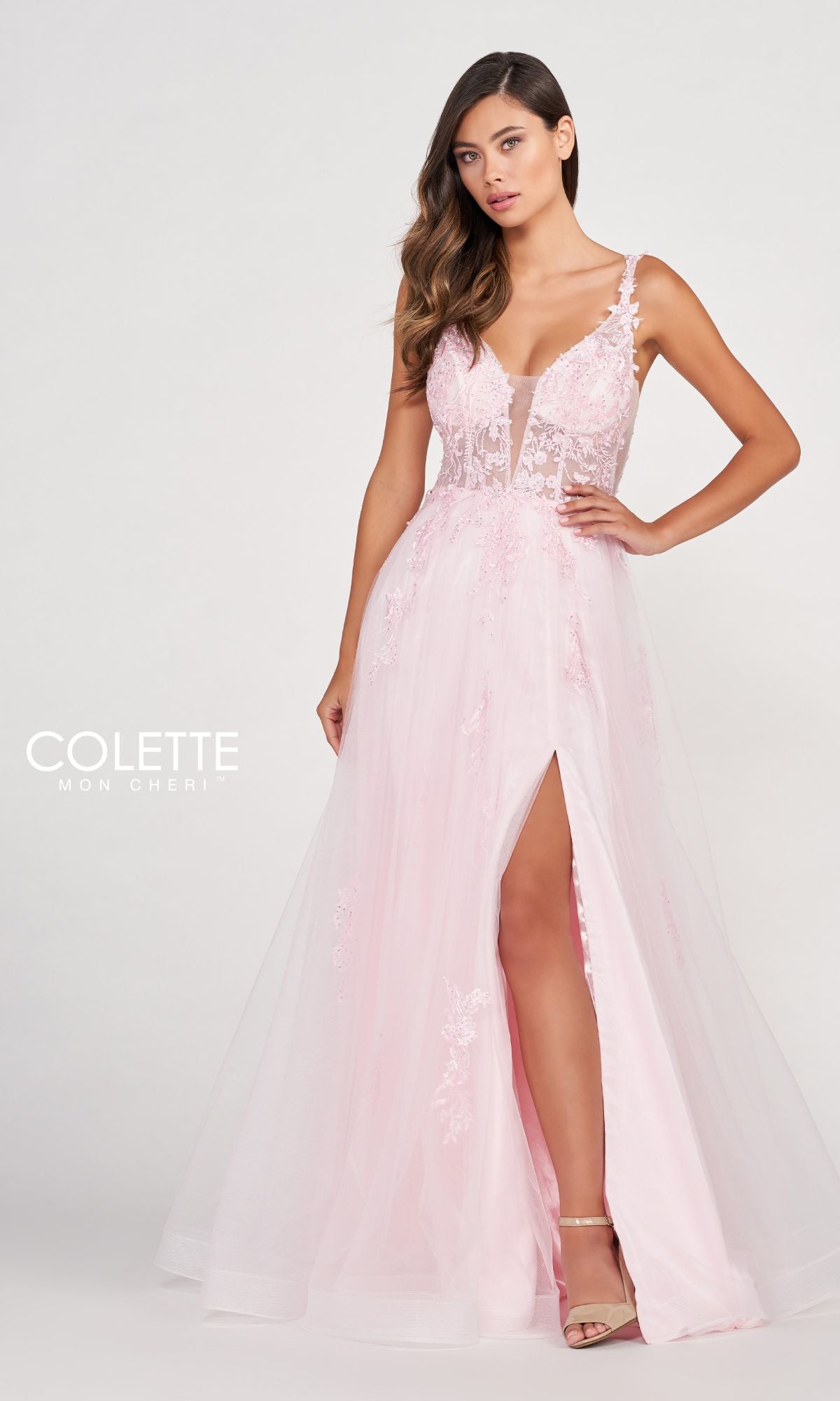 A woman stands against a plain background wearing the CL2074 Tulle A-Line Prom Dress with a sheer bodice in light pink, featuring a deep V-neck, lace appliques, and a high leg slit.
